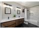 Modern bathroom with double sinks, sleek wood cabinets, black hardware, and tub with marble tile surround at 10245 N 34Th Pl, Phoenix, AZ 85028