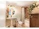 This charming bathroom features a pedestal sink, round mirror, and shower over tub with neutral colored tile at 1445 W Wood Dr, Phoenix, AZ 85029