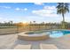Backyard pool and spa with a fence around a golf course, plus palm trees at 15695 W Earll Dr, Goodyear, AZ 85395