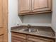 This laundry room features a stainless steel sink, granite countertop, built-in shelves, and wooden cabinets at 15802 N 71St St # 657, Scottsdale, AZ 85254