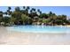 Lagoon-style community pool with sandy beach entry and lush landscaping at 1633 E Lakeside Dr # 143, Gilbert, AZ 85234