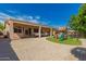 A spacious backyard featuring a play structure, covered patio, and desert landscaping at 16837 W Northampton Rd, Surprise, AZ 85374