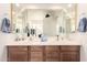 Bathroom featuring double sinks, a large mirror, and wood-finished cabinets at 18077 W Sammy Way, Surprise, AZ 85374
