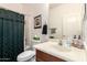 Bathroom featuring a vanity with sink, toilet, and shower with dark green curtain at 18077 W Sammy Way, Surprise, AZ 85374