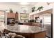 Well-lit kitchen with stainless steel appliances, wooden cabinets, granite counters, and breakfast bar at 18077 W Sammy Way, Surprise, AZ 85374