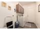 Functional laundry room featuring modern washer and dryer set, storage cabinets, and utility sink at 18077 W Sammy Way, Surprise, AZ 85374
