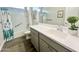 Clean bathroom with a tub, shower, and sink with gray cabinets and a faux plant at 18100 N Piccolo Dr, Maricopa, AZ 85138