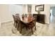 Well-lit dining room with dark wood table, six chairs, a buffet cabinet and wood-look tile flooring at 18100 N Piccolo Dr, Maricopa, AZ 85138