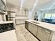 Modern kitchen with stainless steel appliances, light gray cabinets, and an island overlooking the living room at 18100 N Piccolo Dr, Maricopa, AZ 85138
