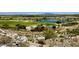 Scenic view of a lush golf course with a tranquil lake and mountain backdrop, surrounded by desert landscape and some homes at 20171 W Cheery Lynn Rd, Buckeye, AZ 85396