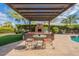 Inviting backyard with a covered patio, outdoor fireplace, putting green, and pool, perfect for outdoor living at 21231 E Nightingale Rd, Queen Creek, AZ 85142