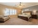 Bright primary bedroom featuring a ceiling fan, neutral paint and carpet, and large windows at 21231 E Nightingale Rd, Queen Creek, AZ 85142