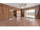 Large living room featuring wood-paneled walls, a ceiling fan, and sliding glass doors leading to the backyard at 3823 W Berridge Ln, Phoenix, AZ 85019