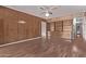 Spacious living room with wood paneled walls, a ceiling fan, wood look floors and a large bookcase at 3823 W Berridge Ln, Phoenix, AZ 85019