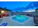 Backyard pool featuring lounge chairs, patio seating, and privacy wall, illuminated against the dusk sky at 4008 N 85Th St, Scottsdale, AZ 85251