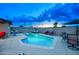 Backyard pool featuring lounge chairs, patio seating, and privacy wall, illuminated against the dusk sky at 4008 N 85Th St, Scottsdale, AZ 85251