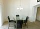 Cozy dining room with a modern glass table, upholstered chairs, and a chandelier at 44147 W Snow Dr, Maricopa, AZ 85138