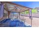 A covered back patio has stylish seating, outdoor lighting and a view of the gravel backyard at 46057 W Dutchman Dr, Maricopa, AZ 85139