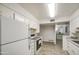 Well-lit kitchen featuring white appliances and cabinets, with consistent tile flooring extending into the next room at 4727 N 50Th Dr, Phoenix, AZ 85031