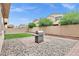 Backyard view with artificial grass lawn, BBQ grill, stone perimeter, and privacy wall at 5223 S Axiom --, Mesa, AZ 85212