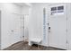Bright foyer with white walls, light-colored wood floors, bench, and a modern glass-paneled front door at 5223 S Axiom --, Mesa, AZ 85212