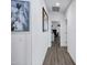 Hallway with wood floors and white walls decorated with framed artwork, leading to a room with an office setup at 5223 S Axiom --, Mesa, AZ 85212