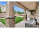 Covered patio with stone-wrapped pillars, gray patio furniture, and artificial grass at 5223 S Axiom --, Mesa, AZ 85212