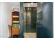 Unique shower featuring blue square tile and glass doors, complemented by a wooden storage unit with towels at 6417 N 52Nd Pl, Paradise Valley, AZ 85253