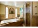 Luxurious bathroom featuring a soaking tub, a glass-enclosed shower, and travertine tile, perfect for relaxation at 6901 E Portland St, Scottsdale, AZ 85257