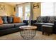 Inviting living room featuring comfortable black leather sofas, a unique round coffee table, and sunlit French doors at 6901 E Portland St, Scottsdale, AZ 85257