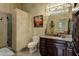 Luxurious bathroom with granite counters, dark wood cabinets, glass shower, travertine floors, and decorative lighting at 9290 E Thompson Peak Pkwy # 409, Scottsdale, AZ 85255