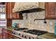 Close up of cook top, hood, and backsplash in a kitchen with custom wood cabinets at 9290 E Thompson Peak Pkwy # 409, Scottsdale, AZ 85255