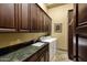 Functional laundry room featuring dark wood cabinets, green countertops, and modern appliances at 9290 E Thompson Peak Pkwy # 409, Scottsdale, AZ 85255
