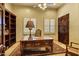 Charming home office with a wooden desk, plush rug, built-in shelves, and shuttered windows at 9290 E Thompson Peak Pkwy # 409, Scottsdale, AZ 85255