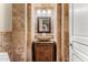 Rustic powder room featuring stone walls, unique vessel sink, and decorative lighting fixtures at 11986 N 134Th Pl, Scottsdale, AZ 85259