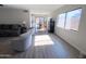 Bright living room featuring wood flooring, neutral walls, and a view of the dining area with natural light at 12934 W Voltaire Ave, El Mirage, AZ 85335