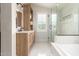 A bright bathroom with a wood-style vanity, a soaking tub and glass-enclosed shower, and tile floors at 13993 N 102Nd St, Scottsdale, AZ 85260