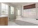 An elegant bathroom featuring a soaking tub, a glass-enclosed shower, and stylish window shutters at 13993 N 102Nd St, Scottsdale, AZ 85260