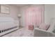 Charming Bedroom featuring a white crib, plush armchair, and delicate pink accents at 13993 N 102Nd St, Scottsdale, AZ 85260