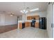 Bright kitchen with tile flooring, wood cabinets, and black appliances with a view to the living area at 14244 N 132Nd Ln, Surprise, AZ 85379