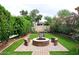 Backyard featuring a circular brick fire pit with built-in seating and lush landscaping, creating a perfect outdoor space at 14605 S 35 Pl, Phoenix, AZ 85044