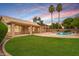 Resort style backyard with refreshing in-ground pool, rock waterfall, mature palm trees, lush lawn and covered patio at 1523 E Tulsa St, Chandler, AZ 85225