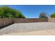 Gravel backyard enclosed by a brick wall with mature trees and clear blue skies above at 15642 N Naegel Dr, Surprise, AZ 85374