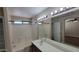 Well-lit bathroom featuring a tub/shower combo, a spacious vanity area, and modern lighting fixtures at 15642 N Naegel Dr, Surprise, AZ 85374