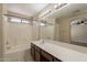 Bright bathroom featuring a combined shower and tub, single sink with a dark wood cabinet and tiled floors at 15642 N Naegel Dr, Surprise, AZ 85374