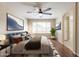 The staged main bedroom features a ceiling fan, wood flooring, and relaxing wall decor with bright, natural light at 15642 N Naegel Dr, Surprise, AZ 85374