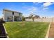 Large grassy backyard with young trees and a covered back patio at 16956 W Alice Ave, Waddell, AZ 85355