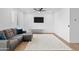 A simple living room featuring a sectional couch and a mounted television at 16956 W Alice Ave, Waddell, AZ 85355