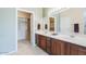 Bathroom showcasing dual sinks, wood cabinetry, and a walk-in closet for ample storage at 17192 W Hermosa Dr, Surprise, AZ 85387
