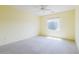Comfortable bedroom with bright yellow walls, neutral carpet, and a window overlooking the landscape at 17192 W Hermosa Dr, Surprise, AZ 85387